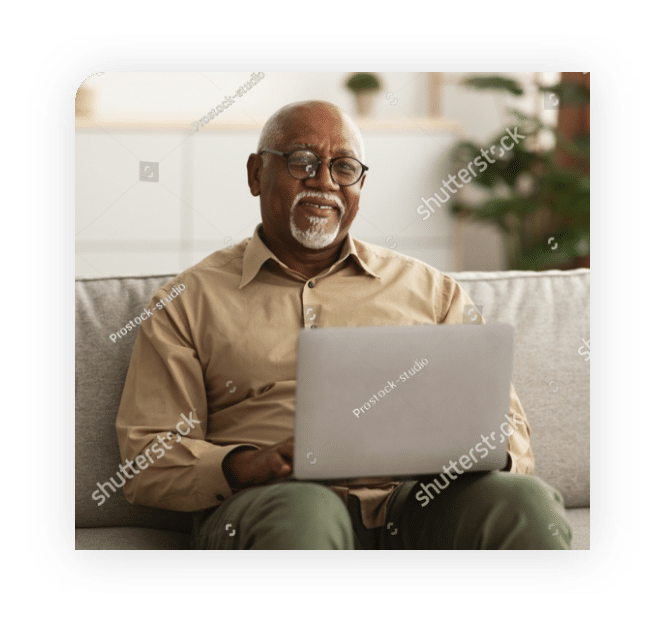 happy-mature-black-man-using-laptop-browsing-internet-smiling-to-camera-working-online-sitting-on